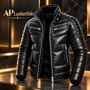 Può includere: Un giubbotto imbottito nero con collo alto, caratterizzato da cuciture orizzontali, cerniere in metallo argentato sul petto e sulle tasche laterali, e una spessa fodera in pelliccia sintetica nera. Il testo AP LeatherHide è visibile in alto.