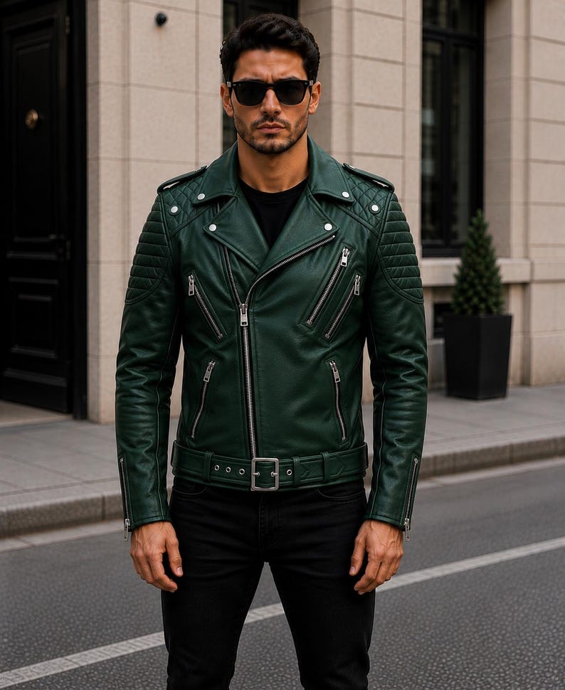 Man wearing green leather biker jacket with quilted sleeves, asymmetrical front zipper and belted waist in an urban evening setting.