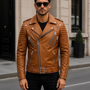 Man wearing cognac leather biker jacket with quilted sleeves, asymmetrical front zipper and belted waist in an urban evening setting.