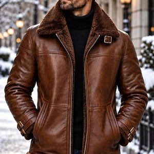 May include: A brown leather jacket with a dark brown faux fur lining, a wide collar, a silver front zipper, and adjustable buckle straps at the cuffs and neck. The jacket is worn over a black turtleneck sweater and dark blue denim jeans.