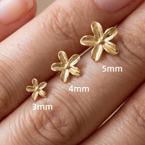 May include: Three gold-toned flower-shaped stud earrings with five petals each. The earrings are labeled with their respective sizes of 3mm, 4mm, and 5mm, indicating the diameter of each individual floral piece in this set of jewelry.