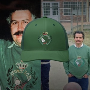 Könnte beinhalten: Grüne Trucker-Cap mit Mesh-Rückseite und gebogenem Schirm. Die Kappe hat ein gesticktes Emblem mit Krone, Golfschläger und dem Text "ESPORTICA Golf". Die Kappe ist einfarbig grün.