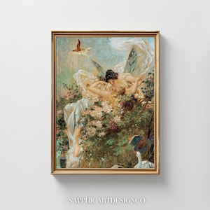 May include: A framed painting featuring a classical scene with two figures, possibly fairies, amidst flowers and foliage. The artwork has a soft color palette with gold accents and a bird in flight. The frame is gold. The text "SAPPHIC ARTDESIGNCO" is at the bottom.