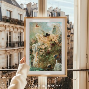 May include: A framed art print featuring a classical painting of a woman with wings, surrounded by flowers and water. The artwork has a soft color palette with gold accents. The print is held up in front of a window with a view of a European-style building.
