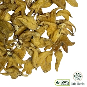 May include: A close-up shot of a collection of dried, light brown herbs with a distinctive, curved form. The herbs are arranged against a white backdrop. The image features a green and white logo that says "100% Organic Fair Herbs."