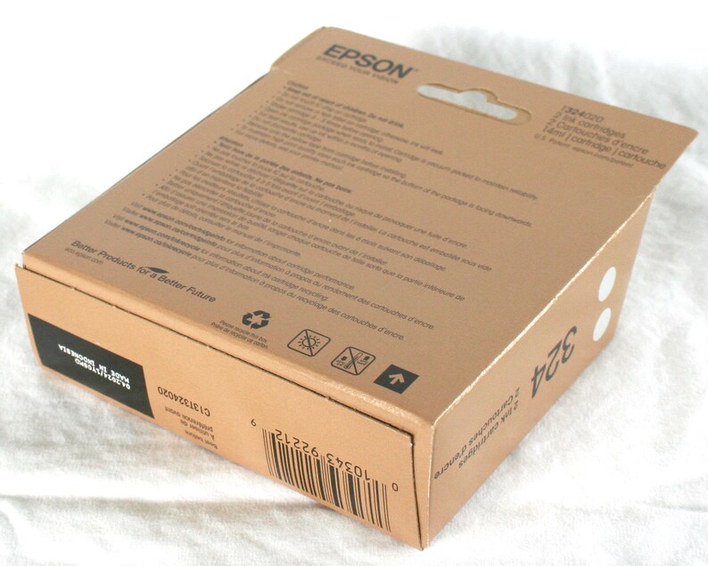 K&ouml;nnte beinhalten: Ein brauner Karton mit einem wei&szlig;en Etikett, auf dem "EPSON" und "Better Products for a Better Future" steht. Die Schachtel enth&auml;lt zwei Tintenpatronen f&uuml;r einen Drucker. Die Schachtel hat auch einen Barcode und den Text "2 Cartridges" und "14ml/cartridge".