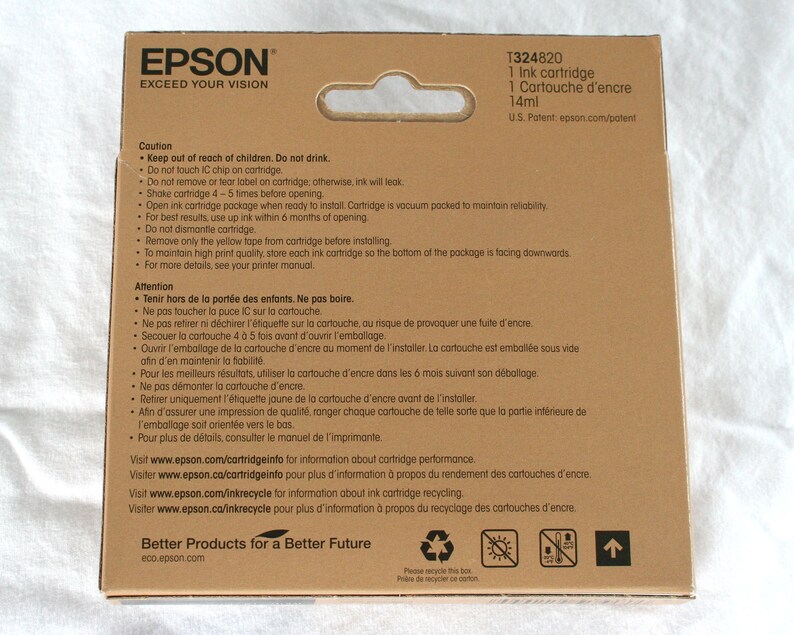 May include: A brown cardboard box with a white label that says "EPSON EXCEED YOUR VISION". The box contains a 14ml ink cartridge for an Epson printer. The label also includes the product number T324820 and the text "1 Ink cartridge, 1 Cartouche d'encre".