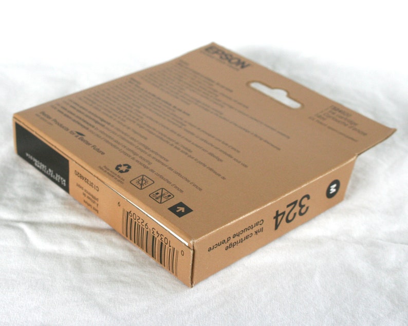 May include: A brown cardboard box with a white label that says "EPSON" and "Ink Cartridge 324". The box has a barcode and a recycling symbol.
