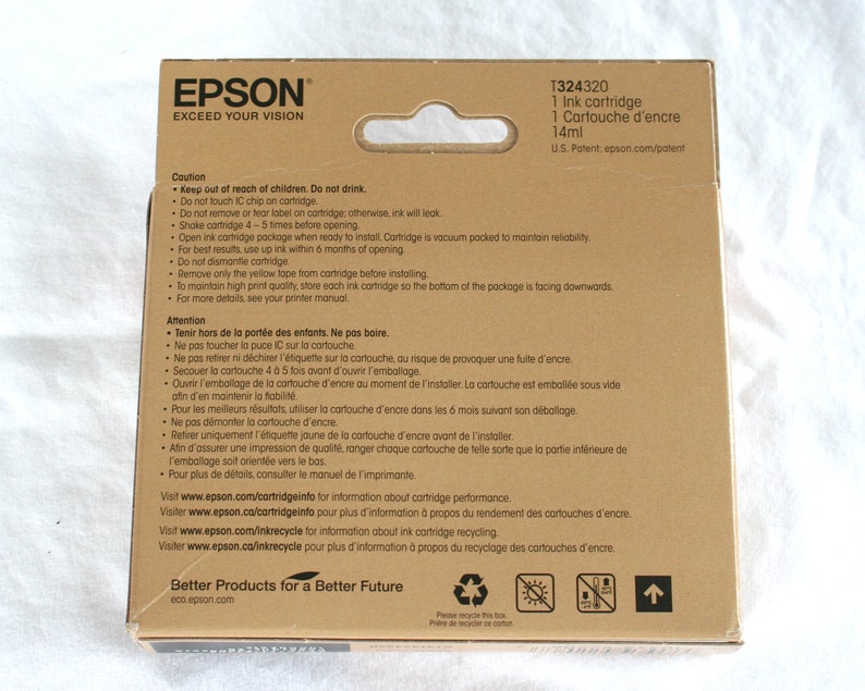 May include: A cardboard box for an Epson T324320 ink cartridge. The box is tan with black text, including the Epson logo and product information. The package contains 14ml of ink and includes safety warnings.