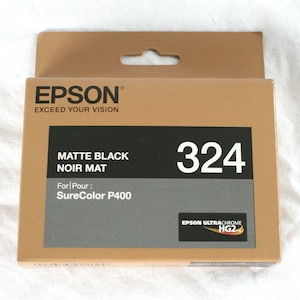 May include: A brown box with a white label that says "EPSON&reg; EXCEED YOUR VISION". The label also says "MATTE BLACK NOIR MAT" and "For Pour: SureColor P400". The box has a white number "324" on it. The box also has a small label that says "EPSON ULTRACHROME HG2".