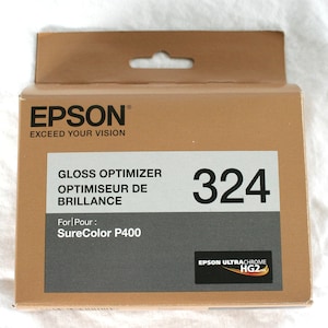 K&ouml;nnte beinhalten: Ein brauner Karton mit einem silbernen Etikett, auf dem "Gloss Optimizer" und "SureColor P400" steht. Der Karton tr&auml;gt au&szlig;erdem die Nummer "324" und den Text "EPSON ULTRACHROME HG2".