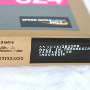 May include: A cardboard box with the text "Best before" and "&Agrave; utiliser de pr&eacute;f&eacute;rence avant". The box also has the text "EPSON ULTRACROME HG2" and "MADE IN INDONESIA". The box is labeled with the code "C13T324320".