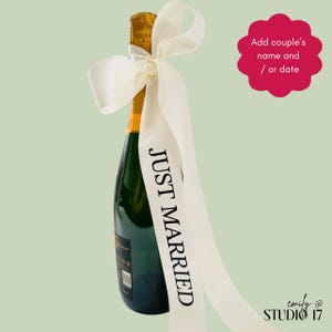 May include: A dark green glass champagne bottle adorned with a long, off-white satin ribbon tied in a bow around the neck. The ribbon features the black text JUST MARRIED printed vertically. A pink scalloped graphic includes the text Add couple's name and / or date.