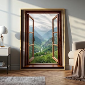 May include: A framed print depicting an open window with a view of a lush green valley and mountains. The window frame is dark brown with a gold border. The landscape features a river winding through the valley.