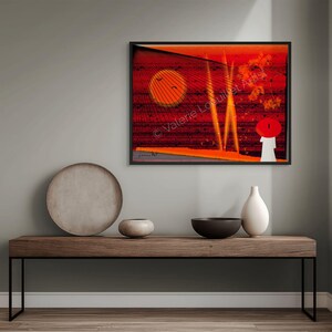 Peut inclure: Impression d'art abstrait dans un cadre noir, avec une palette de couleurs rouge et orange vibrantes. L'œuvre représente un pont stylisé avec un soleil couchant et une figure avec un chapeau rouge. Le nom de l'artiste est visible.