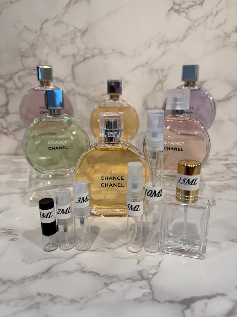 Puede incluir: Una variedad de frascos de perfume y viales de muestra. Se ven varios frascos redondos con tapas plateadas y el texto "CHANCE CHANEL", junto con viales m&aacute;s peque&ntilde;os etiquetados 1ML, 2ML, 3ML, 5ML, 10ML y 15ML.