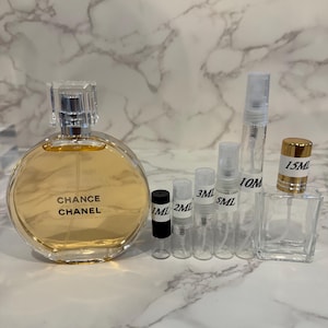 Puede incluir: Un frasco de perfume con el texto "Chance Chanel" junto a varios frascos y viales peque&ntilde;os y transparentes. Los frascos est&aacute;n etiquetados con medidas como 1 ml, 2 ml, 3 ml, 5 ml, 10 ml y 15 ml.