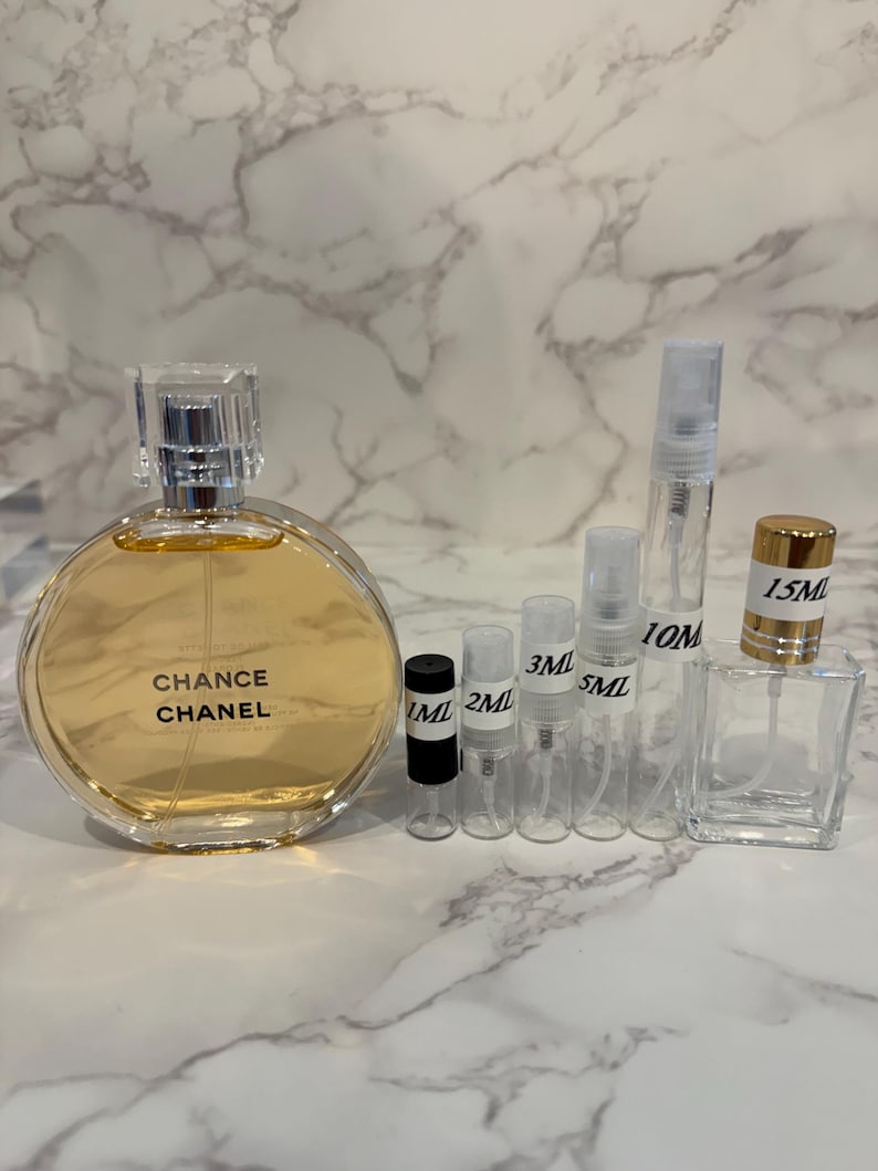 Puede incluir: Un frasco de perfume con el texto "Chance Chanel" junto a varios frascos y viales peque&ntilde;os y transparentes. Los frascos est&aacute;n etiquetados con medidas como 1 ml, 2 ml, 3 ml, 5 ml, 10 ml y 15 ml.
