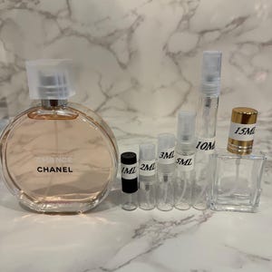 Puede incluir: Una botella de perfume y varios viales peque&ntilde;os y transparentes de diferentes tama&ntilde;os. La botella grande y redonda lleva la etiqueta "Chance" de Chanel. Los viales est&aacute;n etiquetados con medidas de 1 ml a 15 ml, lo que indica tama&ntilde;os de muestra.