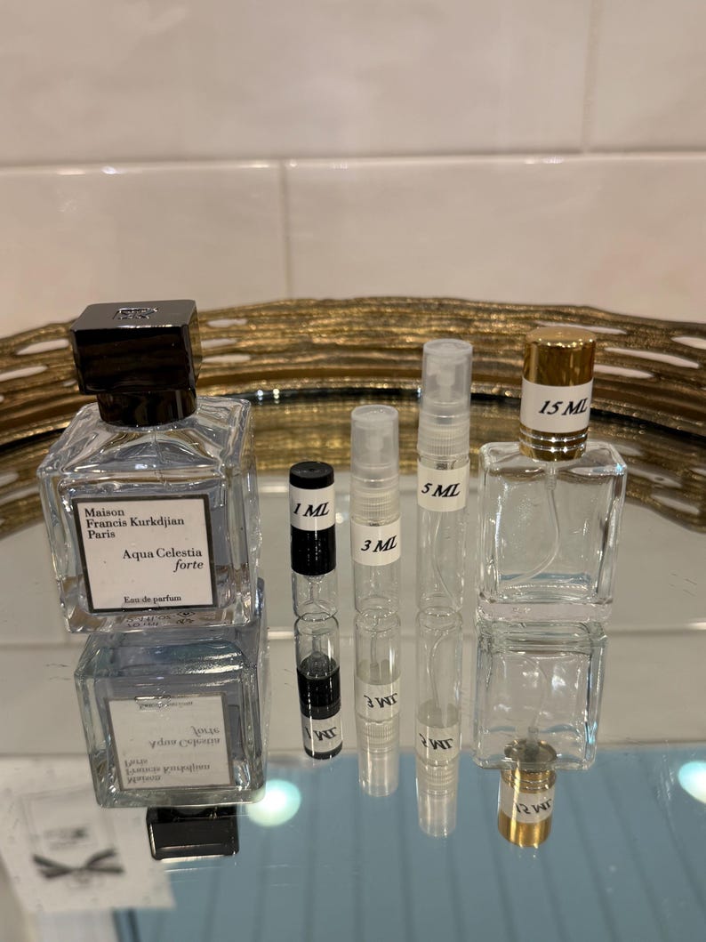 May include: An assortment of perfume bottles and vials on a reflective surface. The bottles include a square glass bottle with a black cap and the text "Aqua Celestia forte". There are also several small vials labeled 1 ML, 3 ML, 5 ML, and 15 ML.