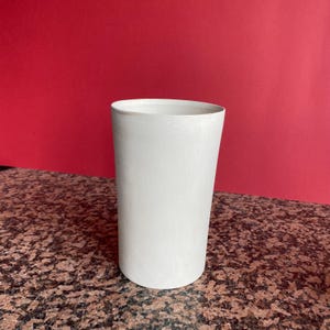 Puede incluir: Un juego de tres tazas de cerámica con acabado mate moteado. Las tazas son de color crema, gris claro y gris oscuro. Cada taza tiene un diseño simple y minimalista.