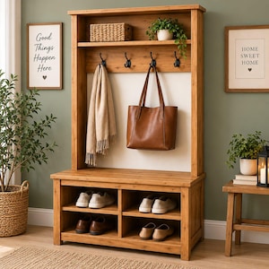 May include: A tall wooden hall tree featuring a bench with four open storage cubbies for shoes, a top shelf with a woven basket and a potted plant, and four black metal hooks holding a beige fringed scarf and a brown leather tote bag.