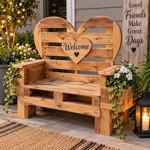 Può includere: Una panchina in legno costruita con legno di pallet, caratterizzata da uno schienale a forma di cuore con una placca centrale a forma di cuore che mostra la parola Welcome e una piccola icona a forma di cuore. Include fioriere laterali con fiori bianchi.