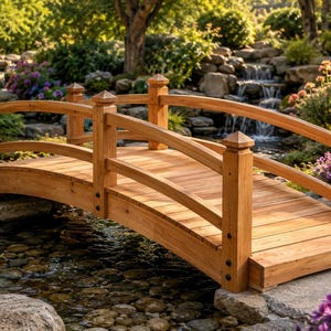 May include: A curved wooden footbridge featuring horizontal railings and vertical posts with pointed caps. The bridge is constructed from light brown planks and is positioned over a small stream with a rocky bed and a waterfall in the background.