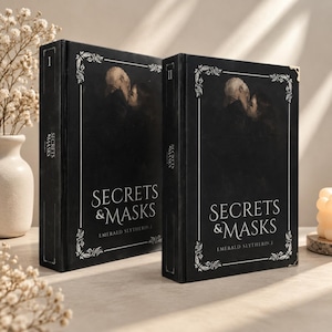 May include: Two black hardcover books titled Secrets & Masks Emerald Slytherin I and II. The covers feature white floral corner borders, a central illustration of two figures, and white serif text. The spines are marked with Roman numerals I and II.