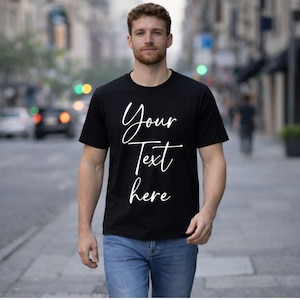 Puede incluir: Camiseta negra con el texto blanco "Your Text here" en fuente cursiva. Cuello redondo. La persona lleva vaqueros azules.