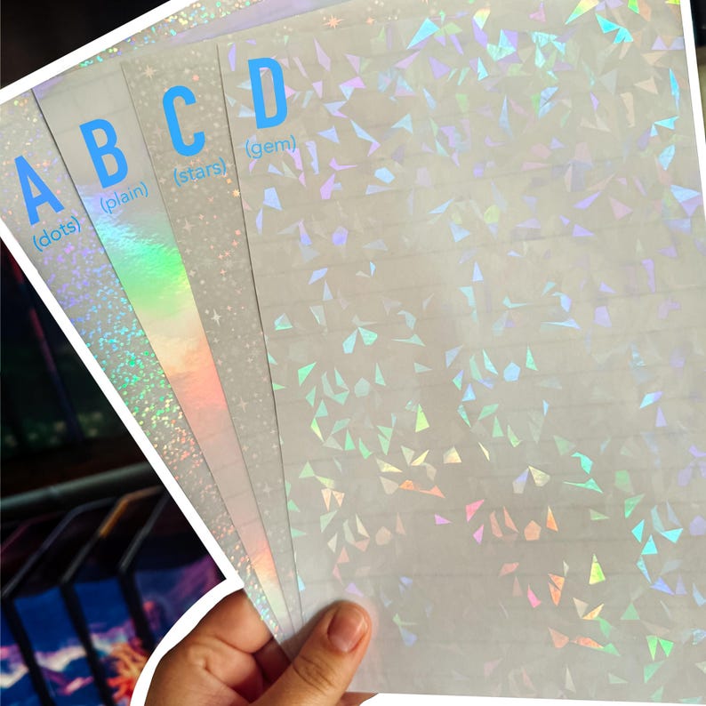 Puede incluir: Una mano sostiene una pila de hojas de papel hologr&aacute;fico blanco. Cada hoja tiene un patr&oacute;n diferente: puntos, liso, estrellas y gema. Las letras A, B, C y D est&aacute;n impresas en azul claro en la parte superior izquierda.