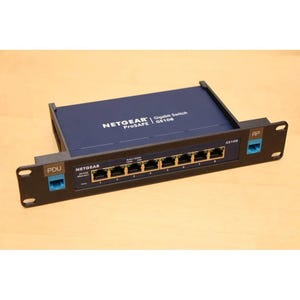 以下が含まれることがあります： 黒いNETGEAR ProSAFE GS108ギガビットスイッチ。スイッチには、金色のコネクタと青色のアクセントが付いた8つのポートがあります。「NETGEAR ProSAFE」と「GS108」の文字がデバイスに表示されています。