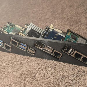 May include: A black rack mount with multiple circuit boards and various ports. The boards are green and blue with silver components. The rack has multiple USB and Ethernet ports.