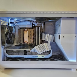 May include: A white desktop computer case with a transparent side panel revealing internal components, including a Gigabyte Radeon graphics card, a CPU cooler, white sleeved power cables, and internal cooling fans with white LED lighting.