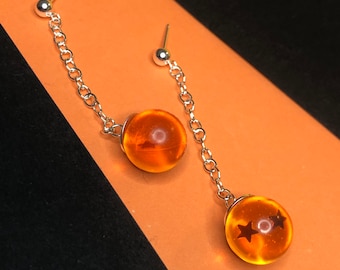 May include: A pair of silver dangle earrings with orange glass spheres. Each sphere has a star design.