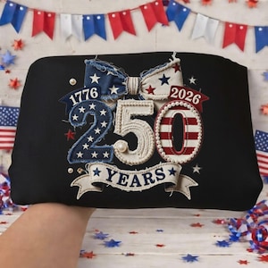 May include: Black tote bag with an embroidered design celebrating 250 years. The design includes the years 1776 and 2026, a bow, the number 250, and the word "YEARS" on a banner, all in patriotic colors.