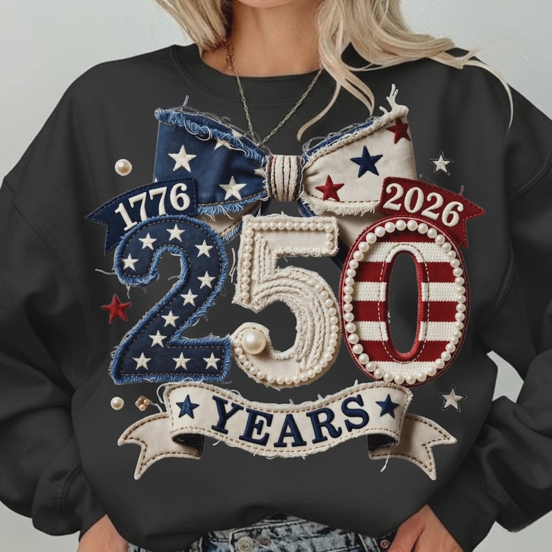 May include: Black sweatshirt with a patriotic design celebrating 250 years. Features a bow with stars, the numbers "1776" and "2026", and the number "250" with the word "YEARS" on a banner. Embellished with stars and pearls.