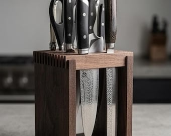 May include: A rectangular dark wood knife block with a slatted top surface holding several kitchen knives and shears. Two large knives with hammered metal blades are suspended vertically within the open frame of the wooden block structure.