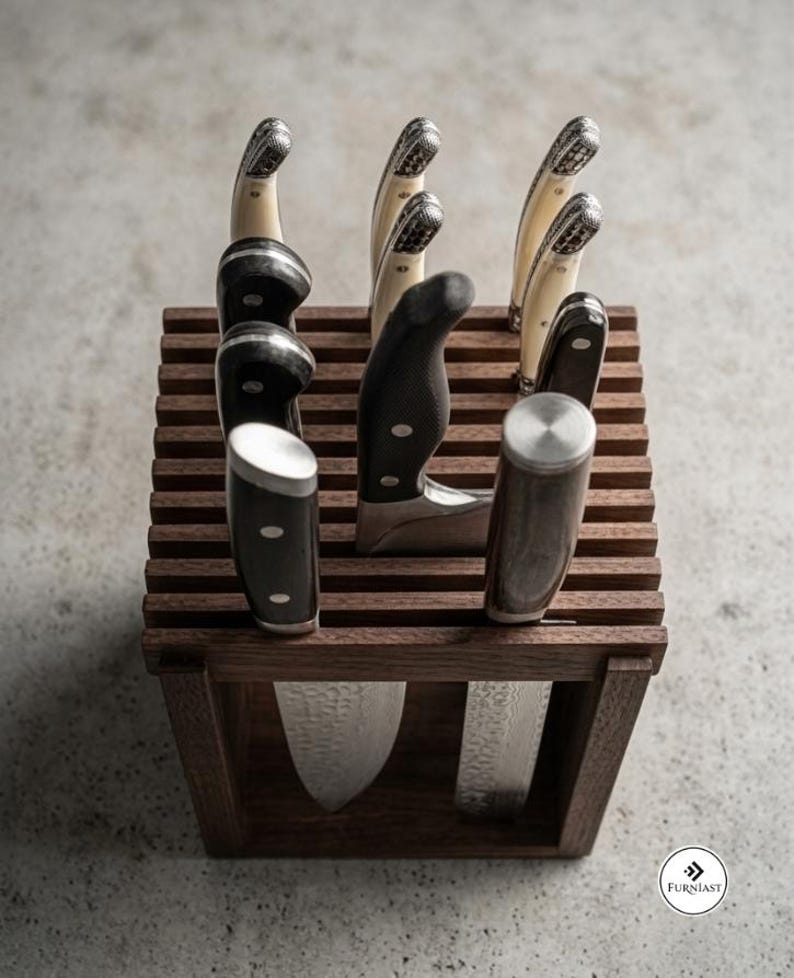 May include: A square wooden knife block with horizontal slats holding several kitchen knives with black and cream-colored handles. The knives feature metallic bolsters and textured blades. The logo Furniast is visible in the bottom right corner.