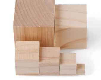 May include: A collection of unfinished wooden blocks of varying sizes, arranged in a stepped pattern. The blocks are rectangular and made of light-colored wood, showcasing the natural grain. The arrangement suggests a building or stacking toy.