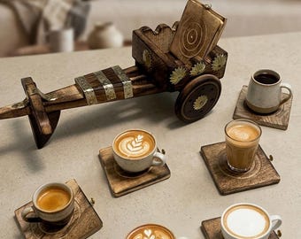 May include: A dark brown wooden cart-shaped holder with gold-toned floral accents, containing a set of square wooden coasters. Five ceramic coffee cups with various latte art designs and coffee preparations are placed on individual square wooden coasters.