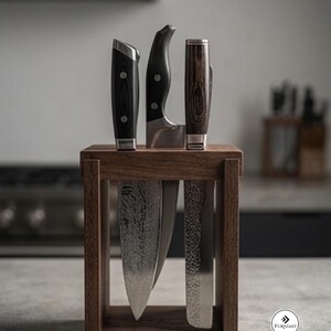 May include: A rectangular wooden knife block holding three kitchen knives with dark handles. The two outer knives feature hammered metal blades, while the center knife has a smooth blade. A small circular logo with the text FURNIAST is visible.