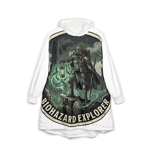 May include: White hooded blanket featuring a graphic of a post-apocalyptic explorer with a gas mask, holding a lantern. The illustration is set against a backdrop of a ruined building and swirling green mist. The text "BIOHAZARD EXPLORER" is printed on the blanket.