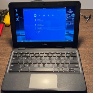 May include: A black Dell laptop with a QWERTY keyboard and a silver trackpad. The screen displays the RetroArch main menu interface with a blue background, system icons, and a sidebar showing technical information including date and time.