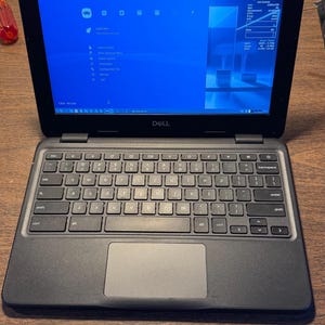 May include: A black Dell laptop with a QWERTY keyboard and a trackpad. The screen displays a blue RetroArch interface with a main menu, system icons, and a sidebar showing system information including the date, time, and hardware usage statistics.
