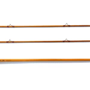Peut inclure: Trois cannes &agrave; p&ecirc;che &agrave; la mouche vintage, de couleur marron clair avec des d&eacute;tails marron fonc&eacute;. Chaque canne pr&eacute;sente des guides en m&eacute;tal et un design classique, sur fond blanc. Les cannes fines semblent &ecirc;tre en bambou.