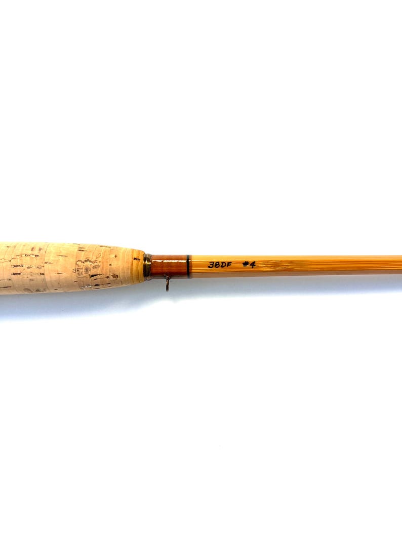 Peut inclure: Une canne &agrave; p&ecirc;che &agrave; la mouche avec une poign&eacute;e en li&egrave;ge et un f&ucirc;t brun clair. Le f&ucirc;t porte l'inscription "38DF #4". La canne est con&ccedil;ue pour la p&ecirc;che &agrave; la mouche.