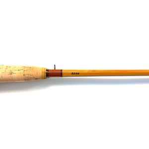 Peut inclure: Canne &agrave; p&ecirc;che &agrave; la mouche vintage avec une poign&eacute;e en li&egrave;ge et un f&ucirc;t en bambou brun clair. La canne a un accent marron fonc&eacute; pr&egrave;s de la poign&eacute;e et le texte "B2/24" imprim&eacute; sur le f&ucirc;t. Sur fond blanc.