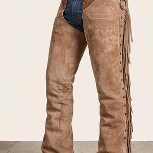 May include: Brown suede chaps with fringe detailing and decorative stitching. The chaps are worn with a brown leather belt with a silver buckle and blue jeans. The chaps are designed to protect the legs and are a staple of Western wear.
