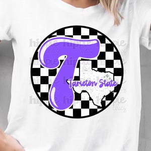 Könnte beinhalten: Weißes T-Shirt mit einem lila Buchstaben "T" in einem schwarz-weiß karierten Kreis. Die Worte "Tarleton State" sind in Lila auf einer weißen Umrandung des Bundesstaates Texas aufgedruckt.